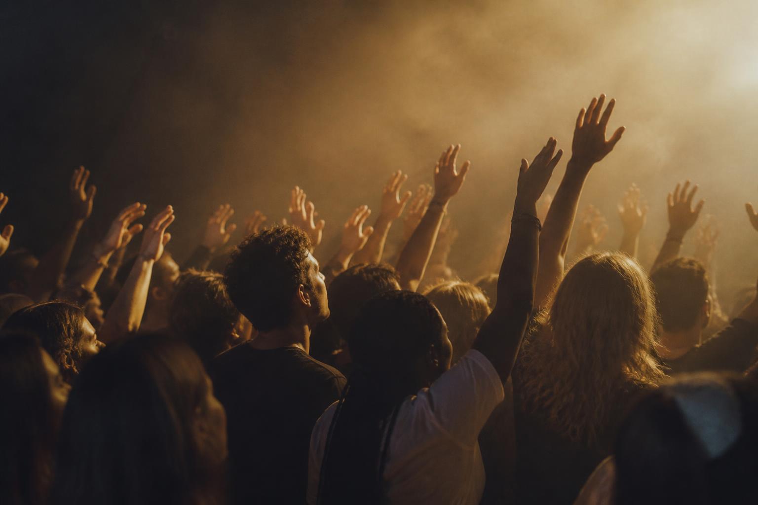 Gen Z aanbidders met handen omhoog tijdens een worship night